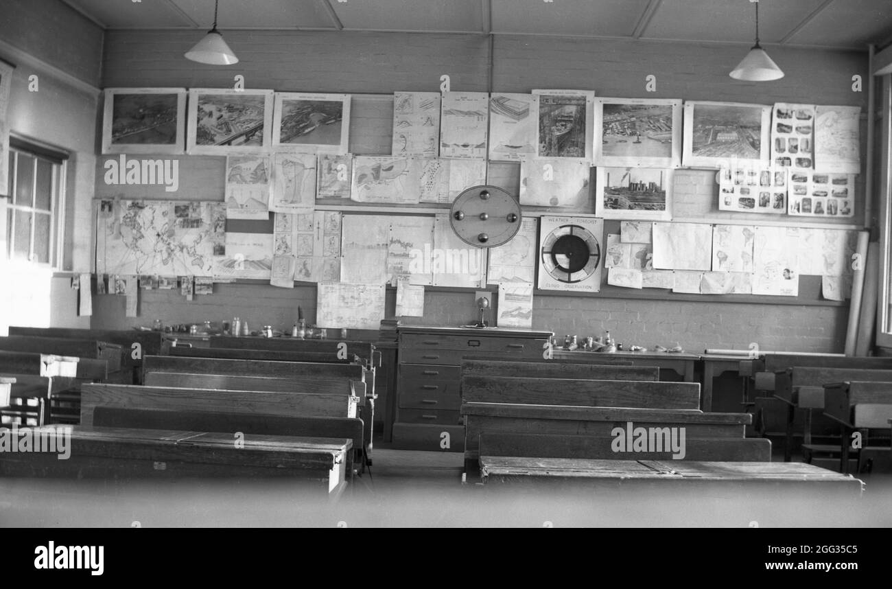 Die 1950er Jahre, historisch, eine Innenansicht eines Schulklassenzimmers, mit Reihen von traditionellen Holzbänken und Schülerklassearbeiten an der Rückwand, Witney, Oxford, England, Großbritannien. Stockfoto