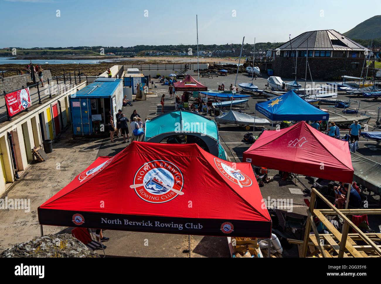 North Berwick, East Lothian, Schottland, Großbritannien, 28. August 2021. UK Wetter: Wassersport. Die Küstenstadt ist voll mit Menschen, die an einem sonnigen und heißen Feiertagswochenende das Meer und Wassersport genießen. Im Bild: Crews aus Küstenruderclubs treten heute in einer Regatta mit den Team-Rastplätzen im Hafen an Stockfoto