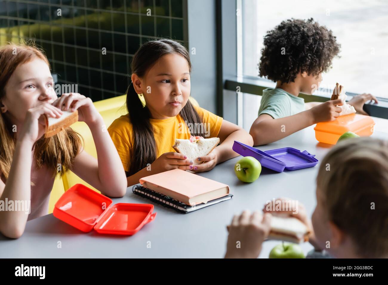 Multiethnische Kinder, die im Schulrestaurant zu Mittag essen Stockfoto