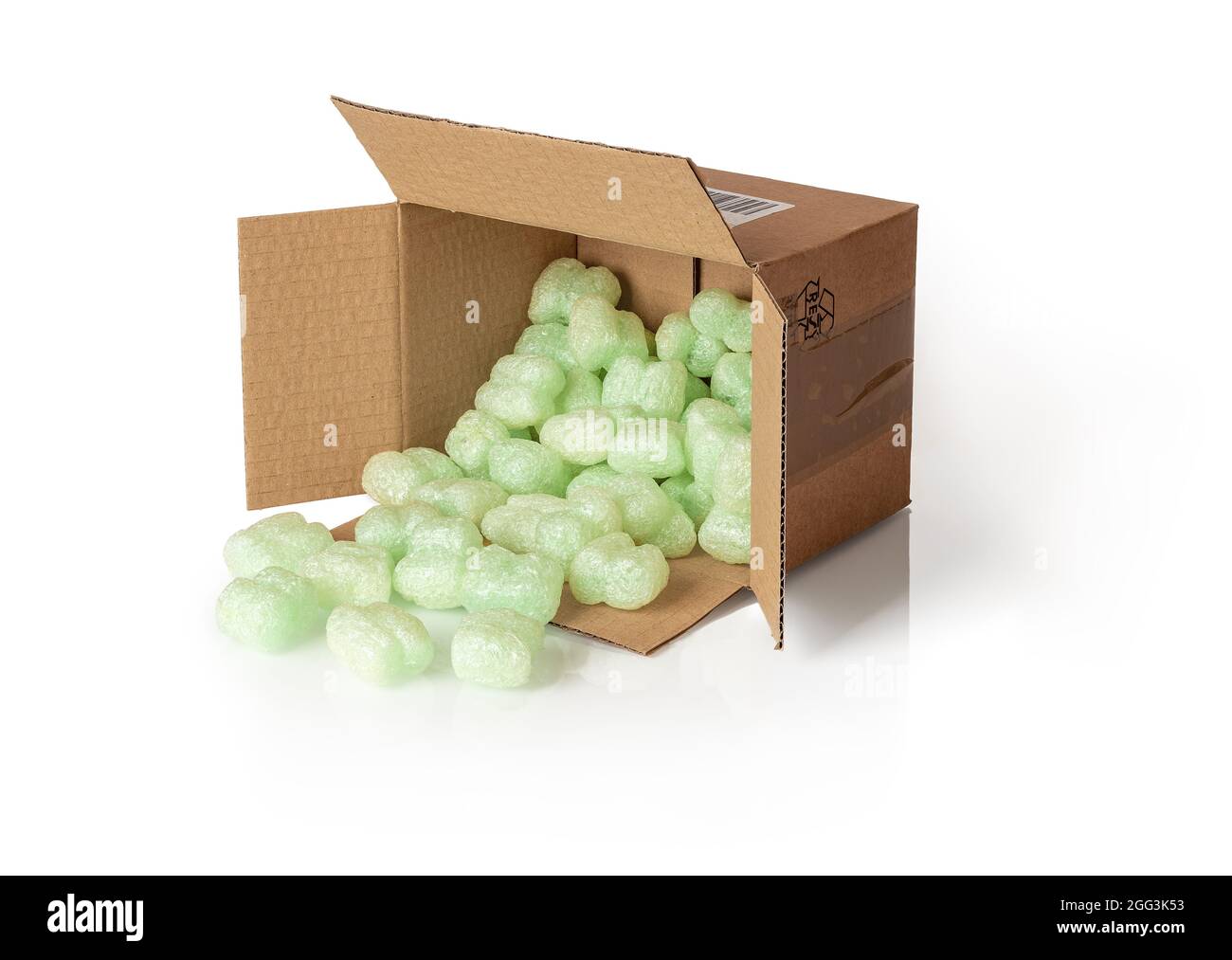 Der Versand von Erdnüssen, die aus dem auf der Seite liegenden Paketkasten verschüttet werden, isoliert auf einem weißen. Braune Kartonschachtel mit losen grünen Schaumstofffüllern zum Schutz Stockfoto