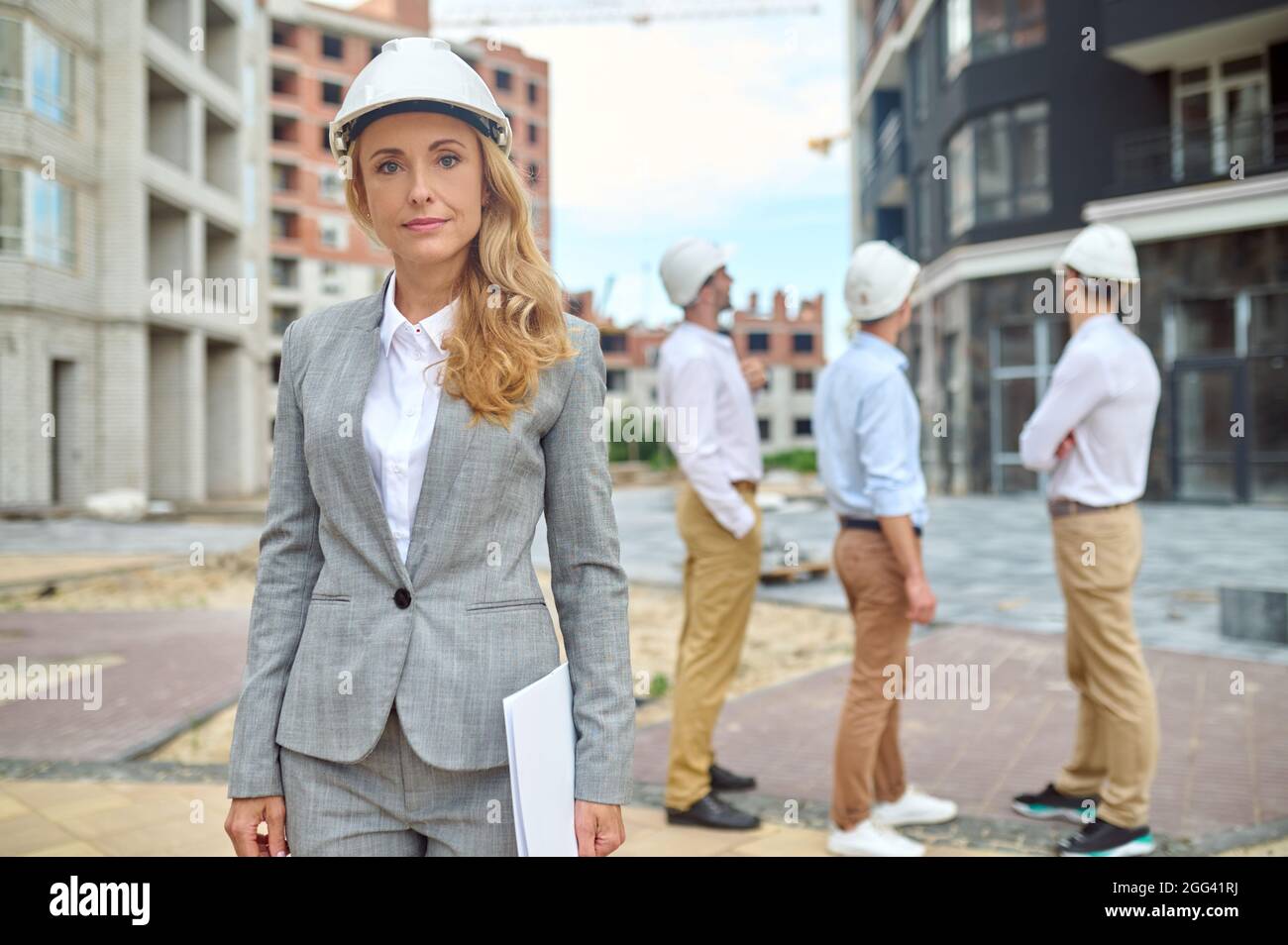 Nette Inspektorin und ihre Kollegen, die den Gebäudebereich inspizieren Stockfoto