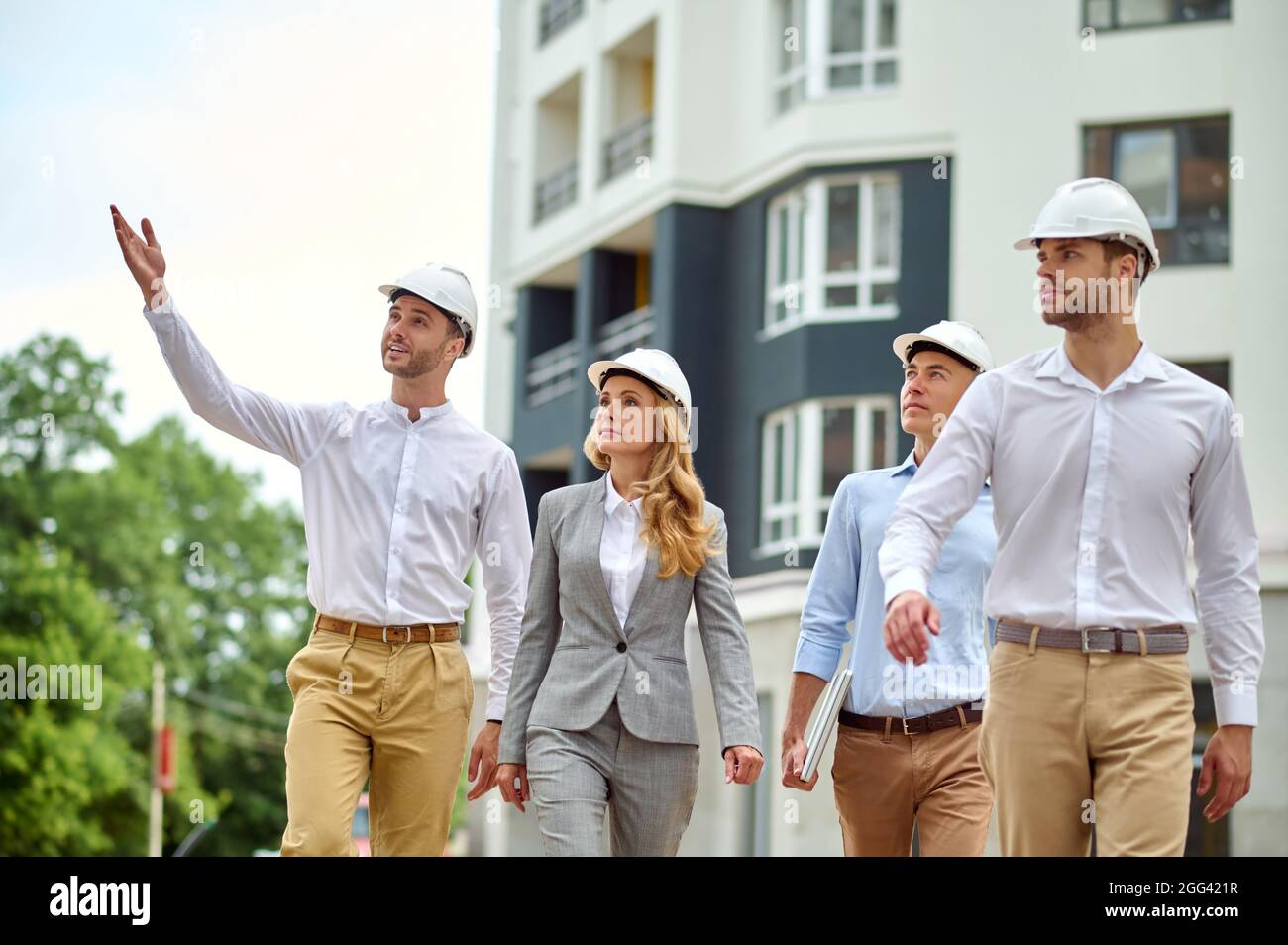 Eine Gruppe von vier Personen mit Schutzhelmen, die den Gebäudebereich inspizieren Stockfoto