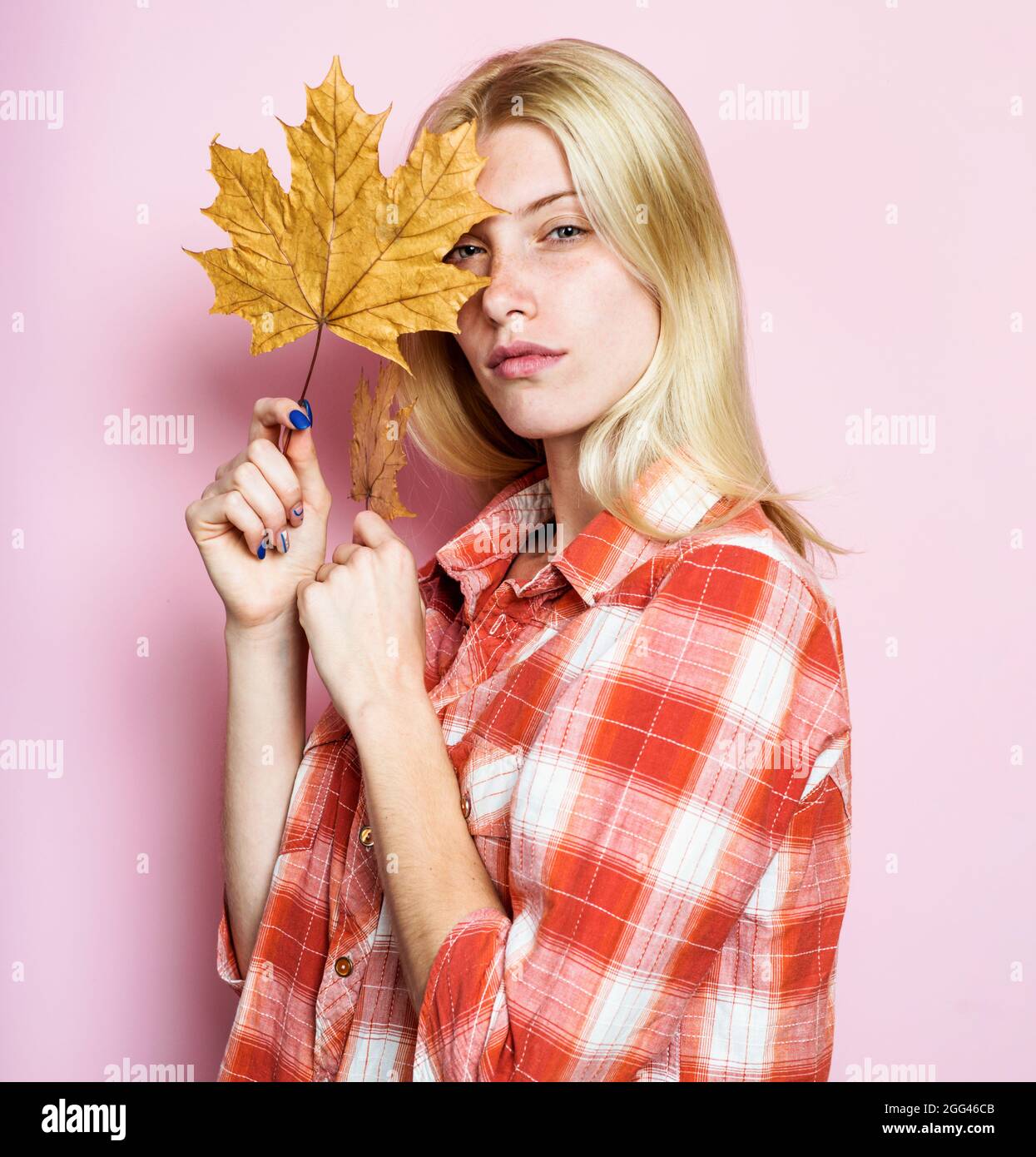 Herbstfrau mit gelben Blättern. Modetrends für den Herbst. Blonde Mädchen in Freizeitkleidung mit goldenem Blatt. Herbstliche Stimmung. Stockfoto