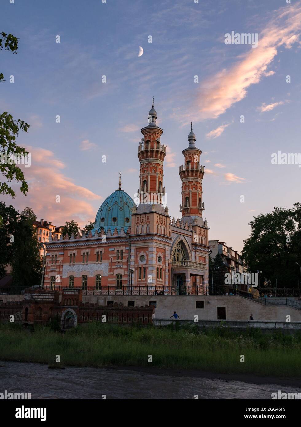 Blick auf die sunnitische Mukhtarov-Moschee vor dem sommerlichen Abendhimmel mit Halbmond und rosa Wolken am Ufer des Flusses Terek in Wladikawkaz, Norden Stockfoto