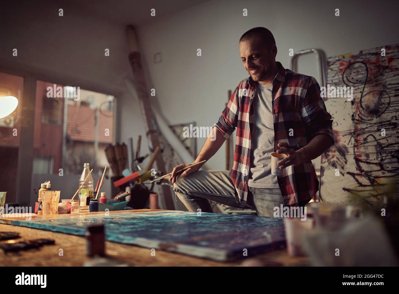 Glücklicher männlicher Maler-Künstler, der im Atelier ein neues Werk schuf Stockfoto