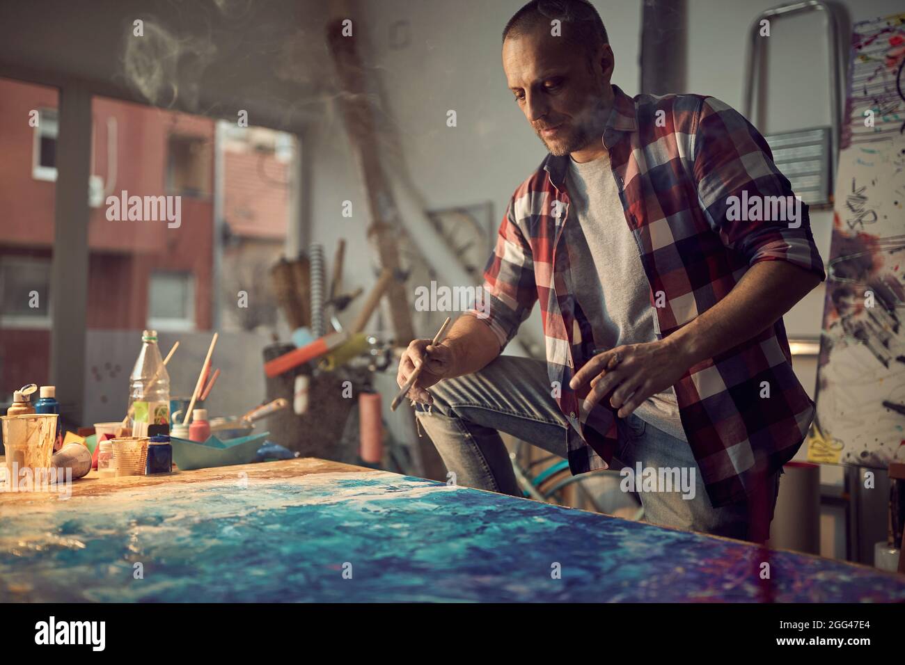 Fokussierter männlicher Malerkünstler, der im Atelier ein neues Werk schuf Stockfoto