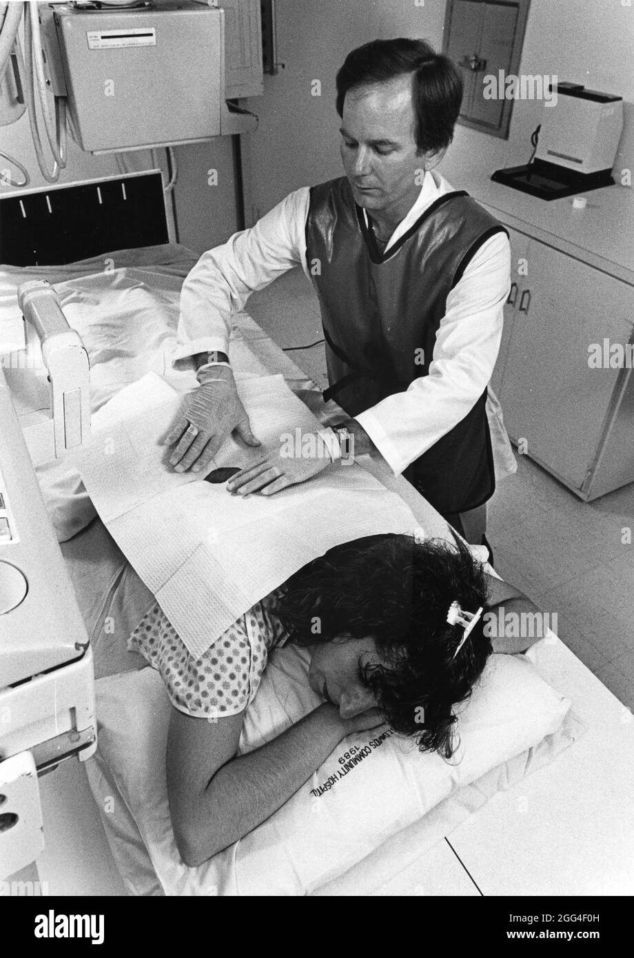 Austin Texas USA, um 1992: Radiologin mit Bleischutzweste bereitet weibliche Patientin auf die myelogramsichen Untersuchungen des Rückenmarks und der Nerven vor. ©Bob Daemmrich Stockfoto