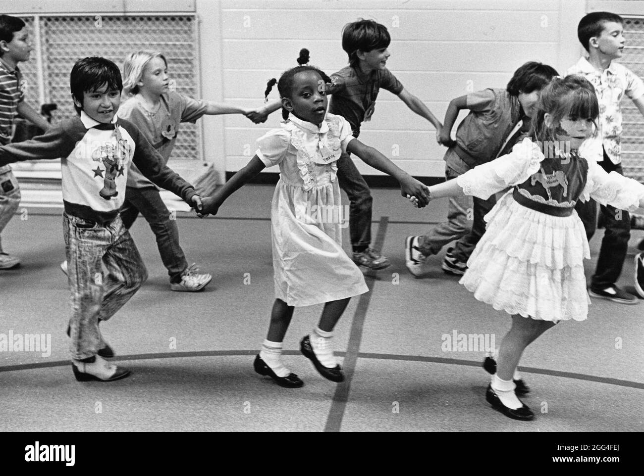 Austin Texas USA, um 1990: Kindergärtnerinnen halten sich die Hände und tanzen während der Sportausbildung in der Turnhalle der Walnut Creek Elementary School. HERR es-0010 ©Bob Daemmrich Stockfoto