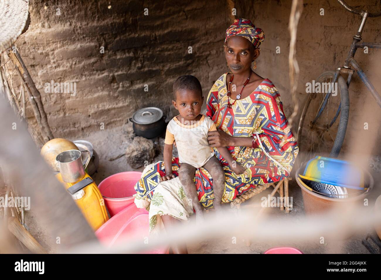 Eine Fulani-Afrikanerin und ihr kleiner Junge vor ihrer kleinen Hütte in der Region Ségou, Mali, Westafrika. Stockfoto