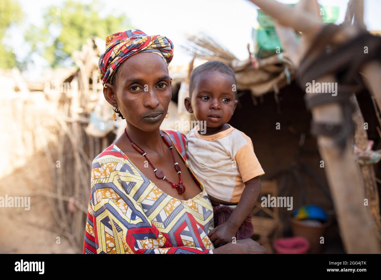 Eine Fulani-Afrikanerin und ihr kleiner Junge vor ihrer kleinen Hütte in der Region Ségou, Mali, Westafrika. Stockfoto