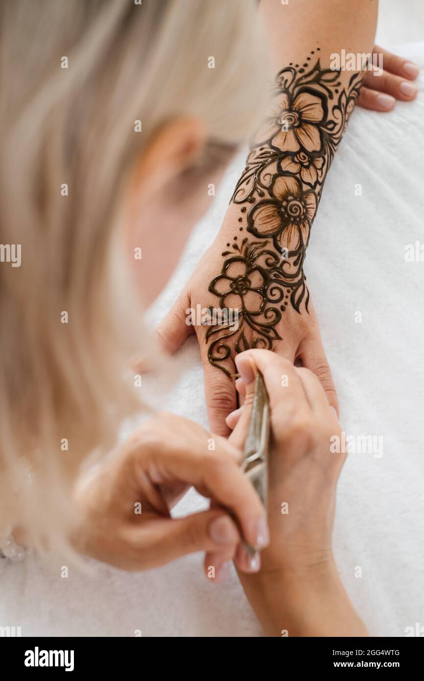 Mehndi Künstler Zeichnung floralen Henna Tattoo auf Frau Hand im Schönheitssalon. Meister, der traditionelle Mehendi-Muster für die Braut vor der Hochzeit anwendet. Stockfoto