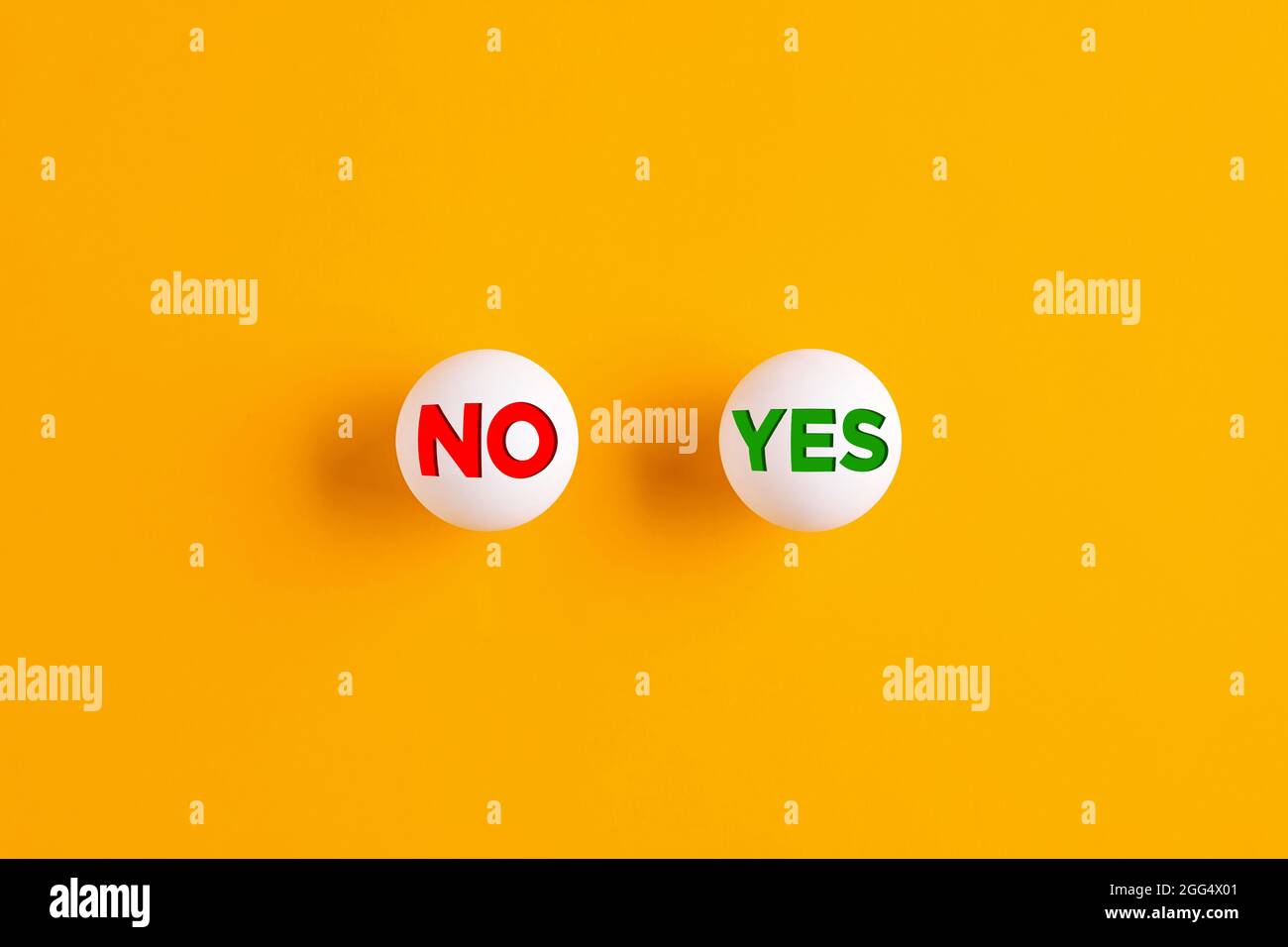 Die Worte nein und ja auf Tischtennisbällen auf gelbem Hintergrund geschrieben. Stockfoto