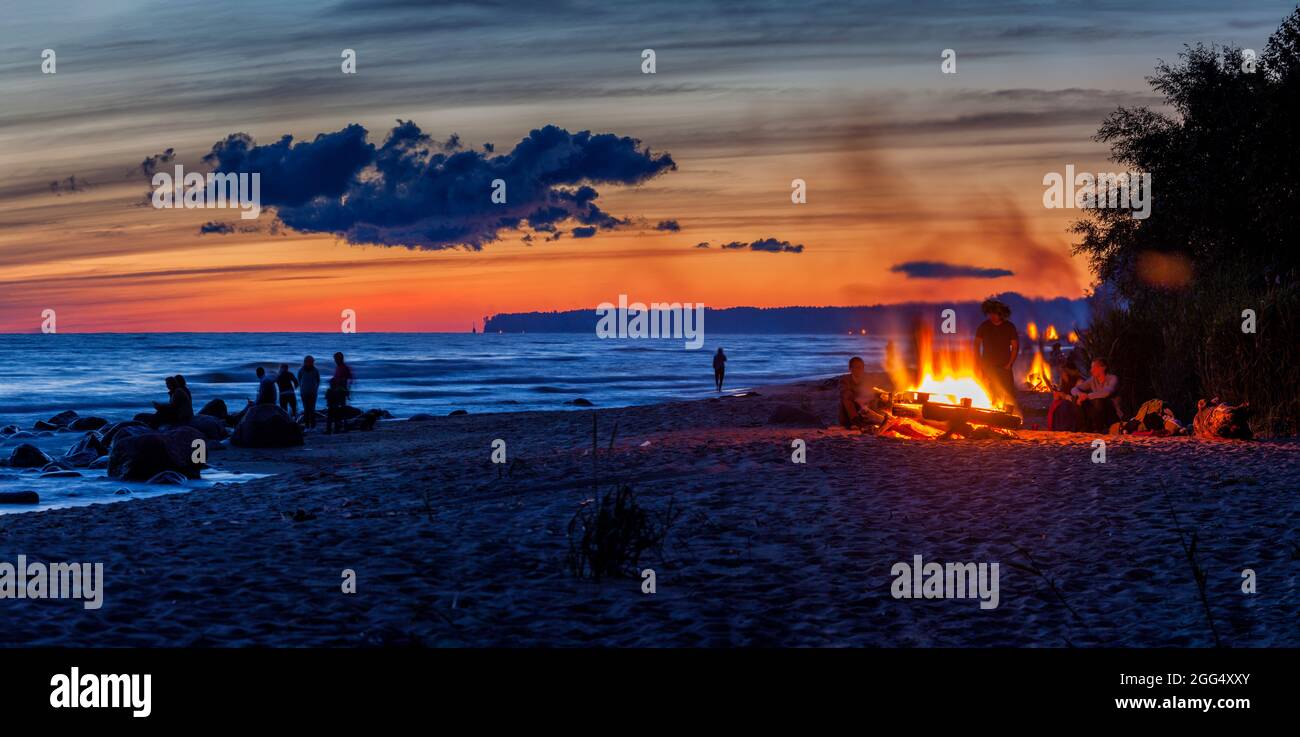 Nicht erkennbare Menschen feiern Sommersonnenwende mit Lagerfeuer am Strand Stockfoto