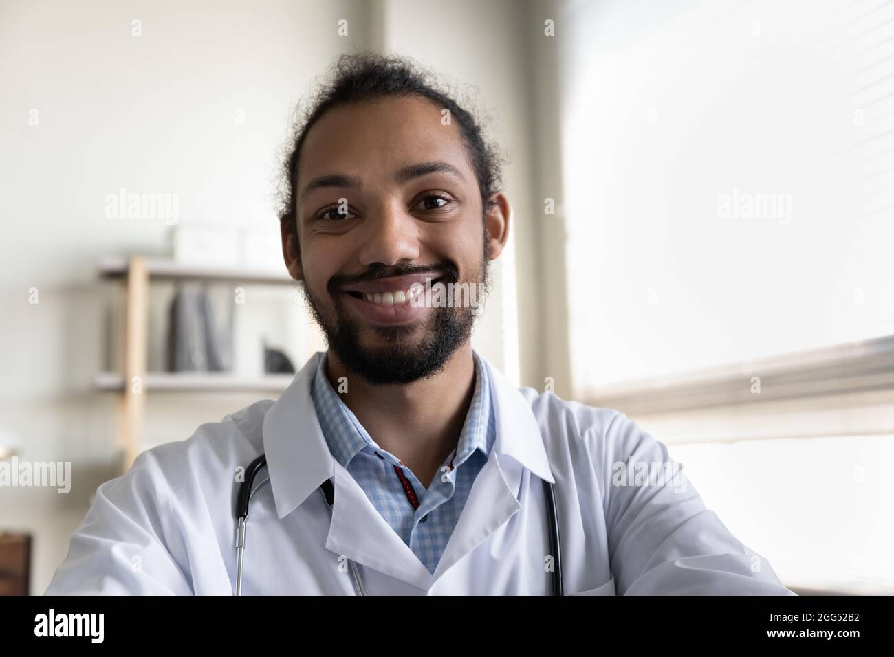 Lächelnder, freundlicher junger afroamerikanischer Arzt, der ein Videogespräch führt. Stockfoto
