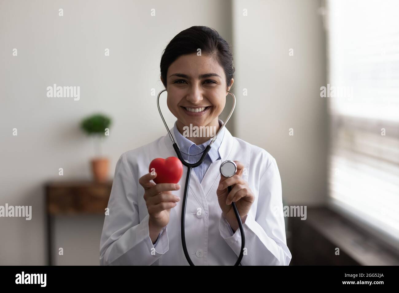Lächelnder junger indischer Kardiologe, der an ein regelmäßiges Kontrollmeeting erinnert. Stockfoto