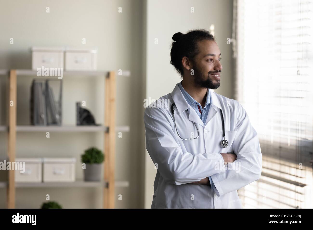 Lächelnder, verträumter junger afroamerikanischer Arzt, der in die Ferne blickt. Stockfoto