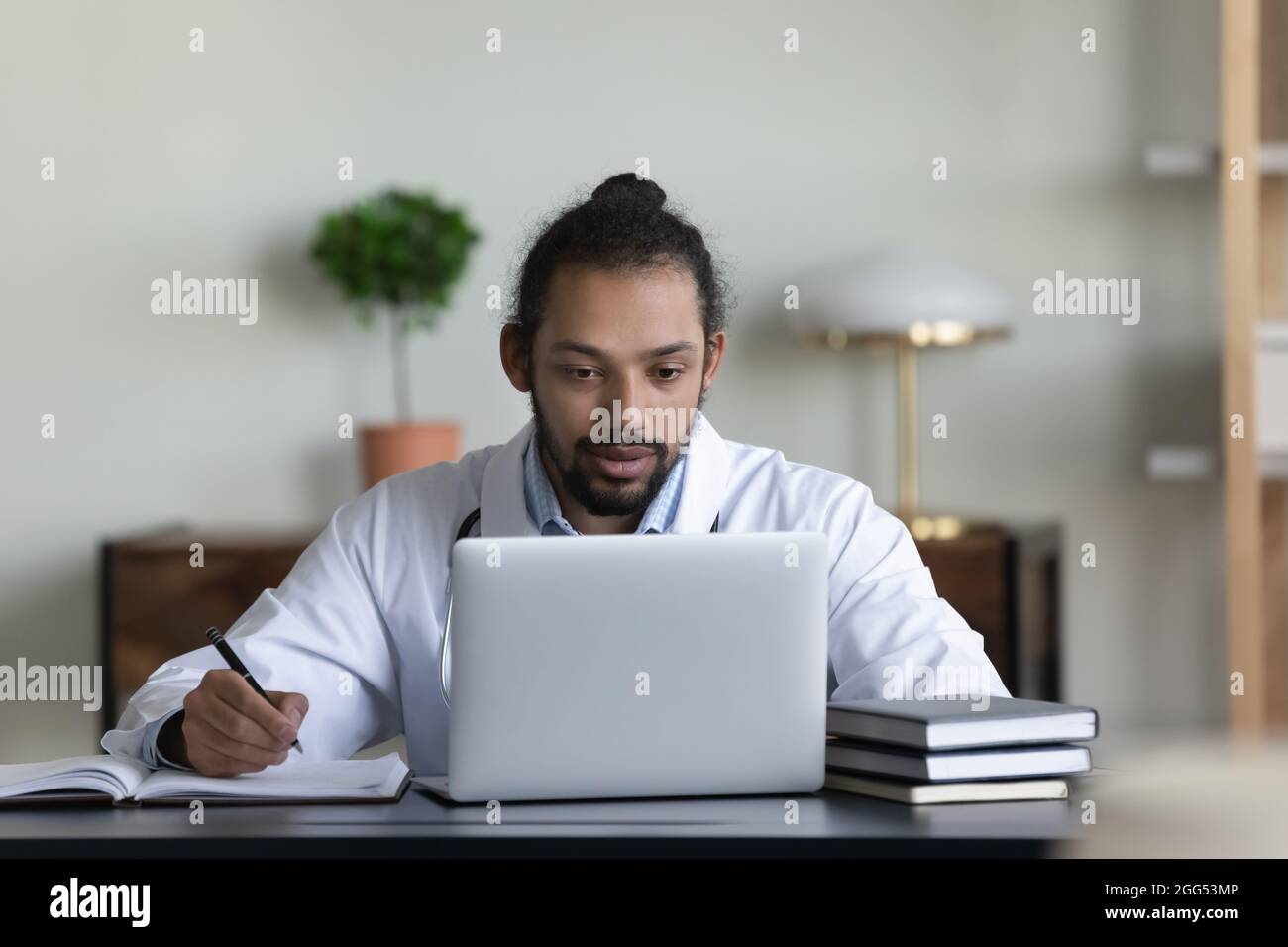 Konzentrierter junger afroamerikanischer Arzt, der am Computer arbeitet. Stockfoto