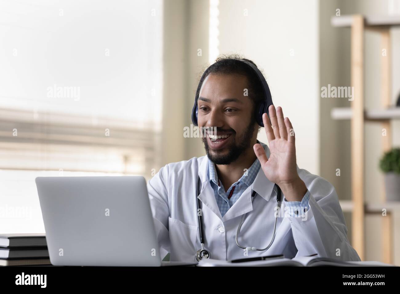 Fröhlicher, freundlicher junger afroamerikanischer Arzt, der ein Videoanrufsmeeting hält. Stockfoto