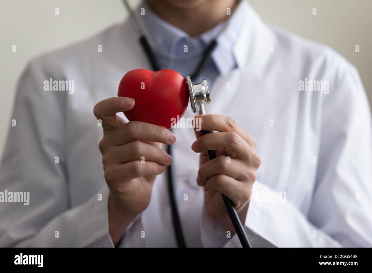 Nahaufnahme junger Arzt, der Stethoskop an Herzfigur setzt. Stockfoto