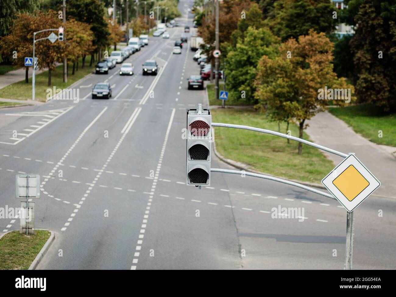 Ampel mit rotem Signal. Über der Straße hängt eine Ampel mit Gebäuden