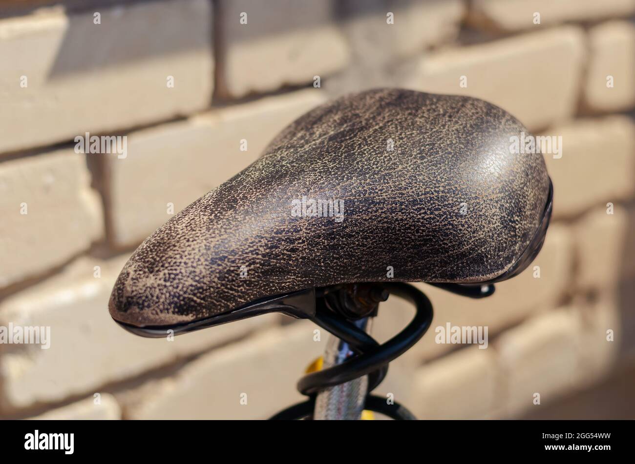 Ein alter Fahrradsitz aus Leder in Nahaufnahme. Der zerrissene Zimt-Sitz  gegen die weiße Steinwand. Sommerzeit. Selektiver Fokus. Draußen  Stockfotografie - Alamy