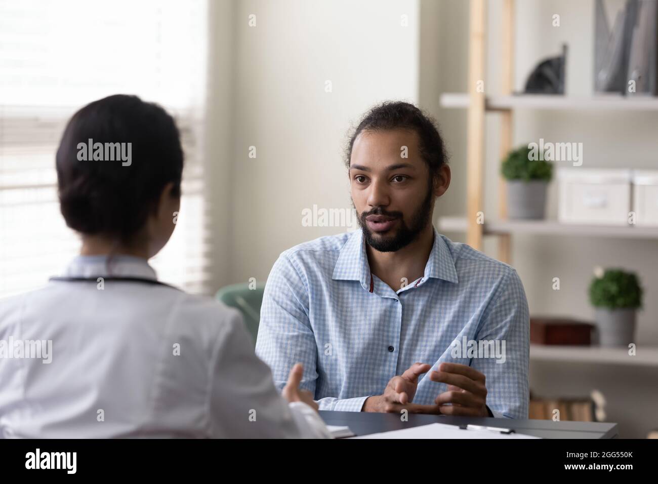 Junge afroamerikanische Patientin, die mit einem Arzt über die Behandlung von Krankheiten spricht. Stockfoto
