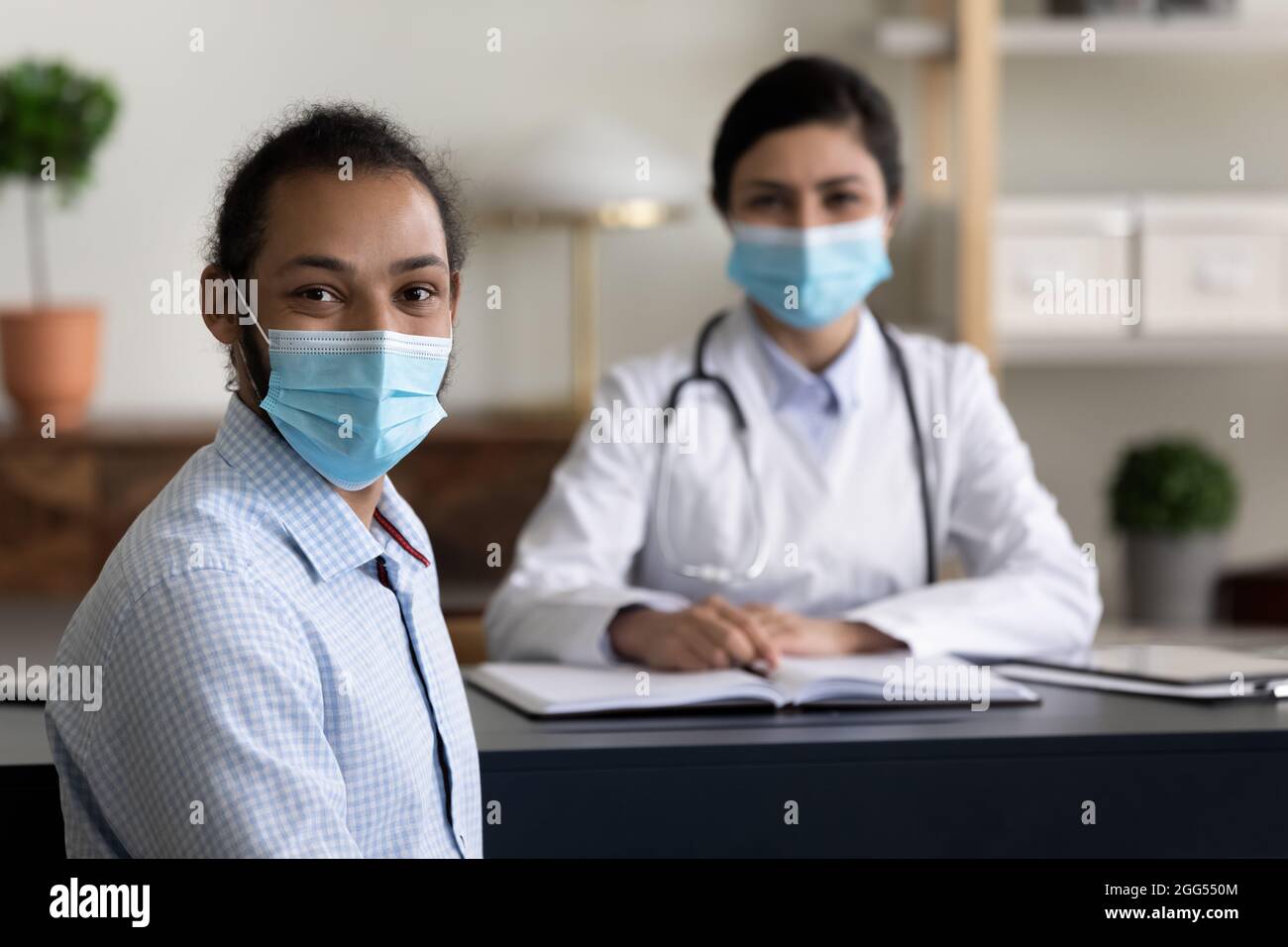 Glücklicher junger afrikanischer Patient posiert in der Klinik mit indischem Arzt. Stockfoto