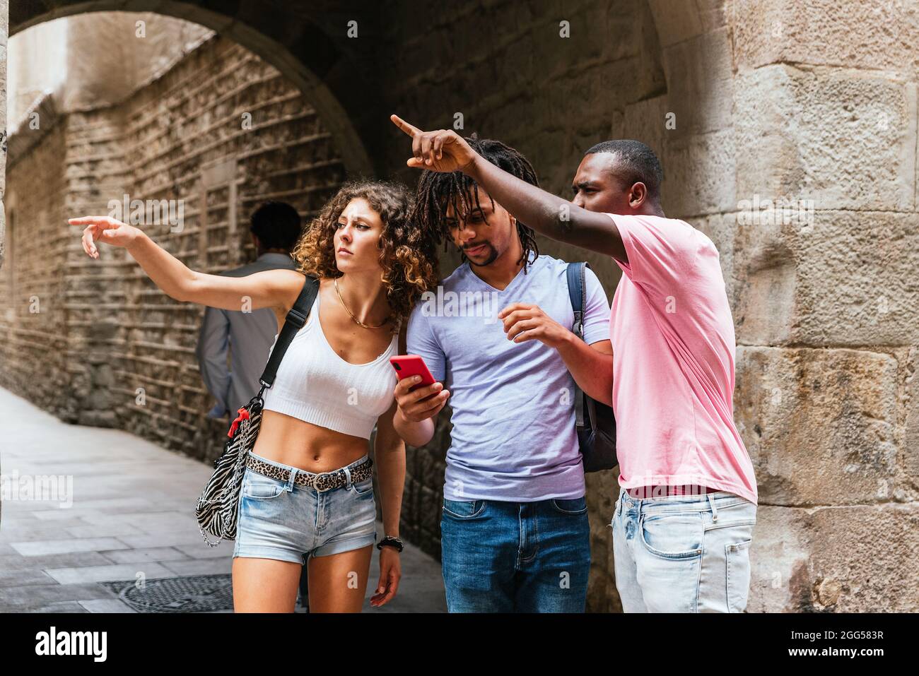 Multiethnische Gruppe von jungen Touristen, die auf der Karte App auf dem Telefon die Route für ihren Besuch in Barcelona überprüfen Stockfoto