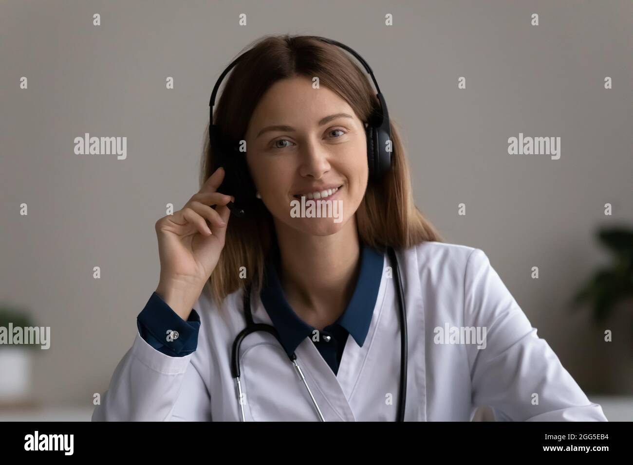 Porträt eines glücklichen, erfahrenen jungen Arztes im Headset. Stockfoto