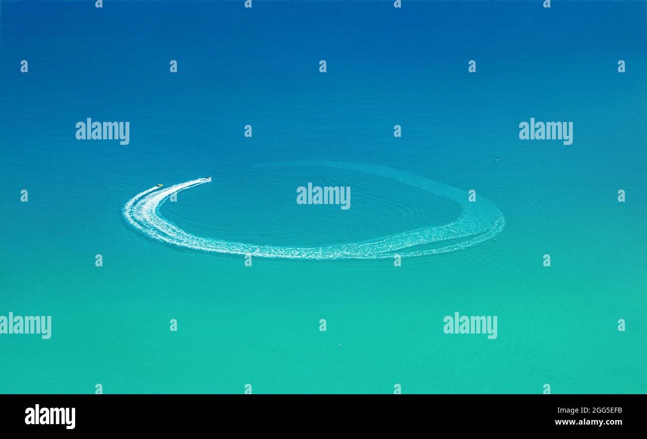 Wassersport am Strand Luftbild. Schnellboot und Wellengleiter verlassen den Rundweg auf dem Wasser Stockfoto