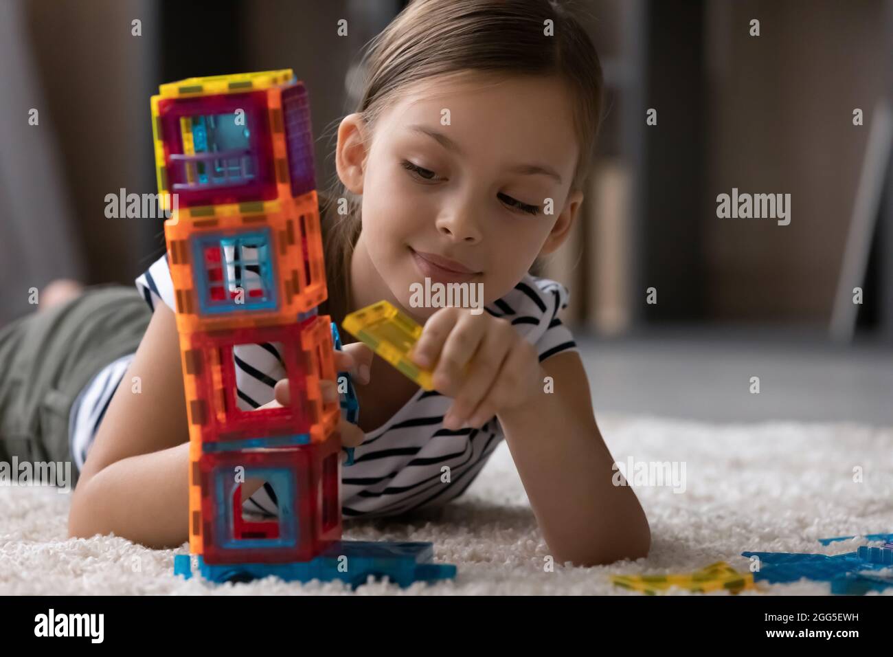 Glücklich preteen Kind Mädchen spielend Spielzeug, liegend auf Teppich. Stockfoto