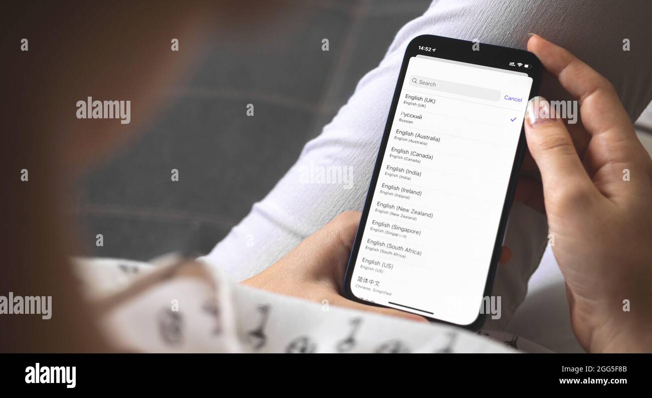 Frau, die die Sprache auf ihrem neuen Mobiltelefon wählt, Spracheinstellungen auf den Smartphones Stockfoto