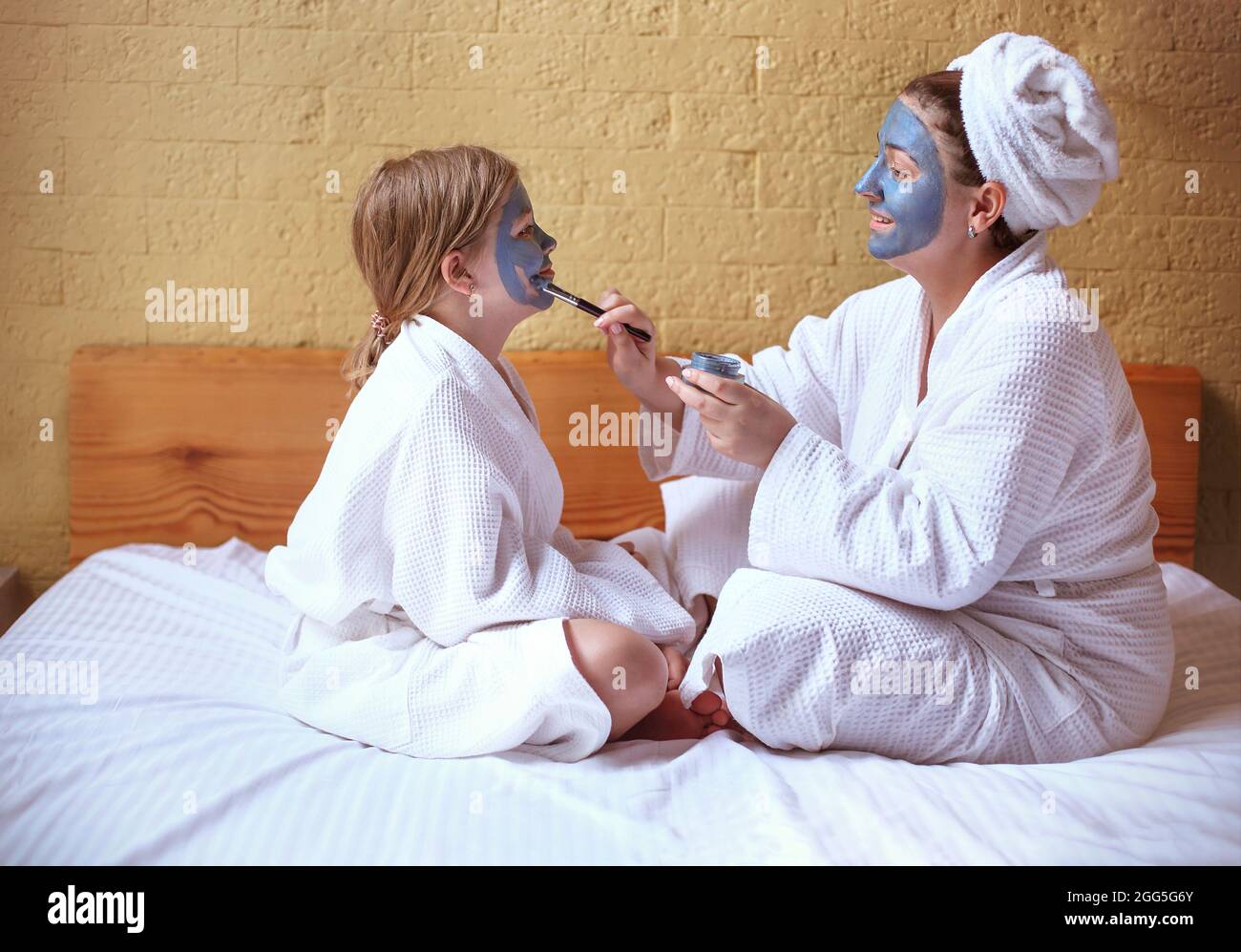 Glückliche Familie Mutter und Baby Tochter machen Gesichtsmaske, Hautpflege zusammen Stockfoto