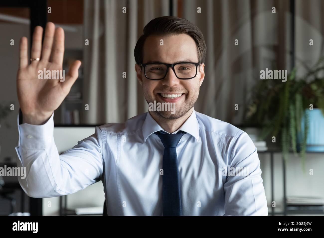 Porträt eines lächelnden Geschäftsmannes in einer Hand winkenden Brille Stockfoto