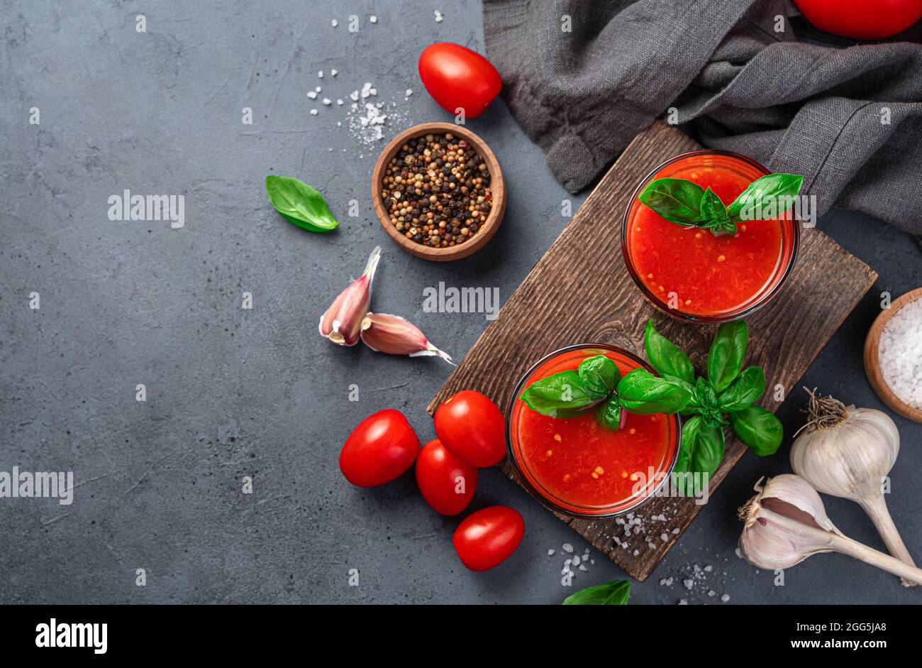 Tomatensaft, Gewürze, Basilikum, Salz und Knoblauch auf grau-blauem Hintergrund. Stockfoto