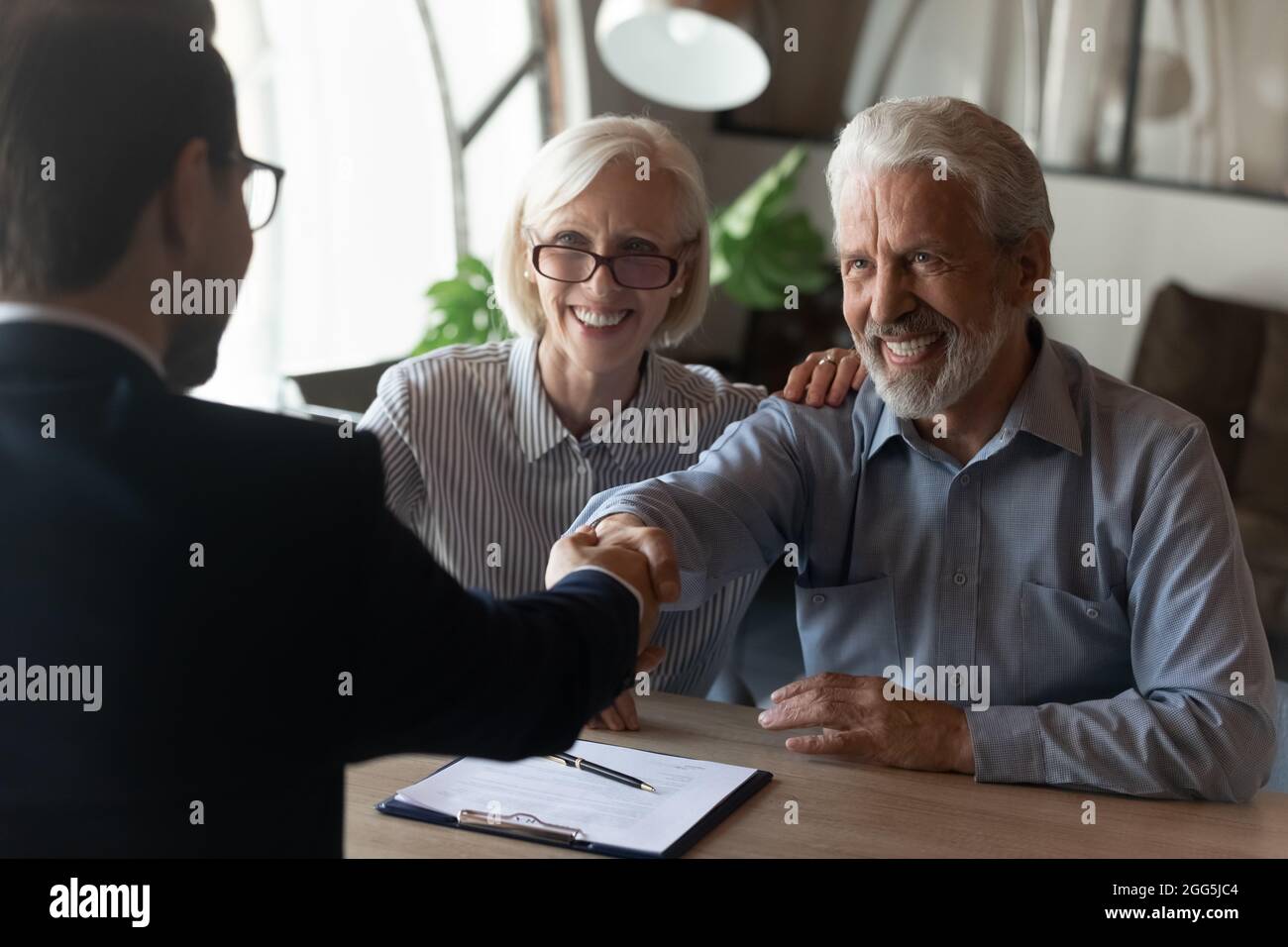 Aufgeregt reifes Paar schüttelt Manager Geschäftsmann Hand bei der Sitzung Stockfoto