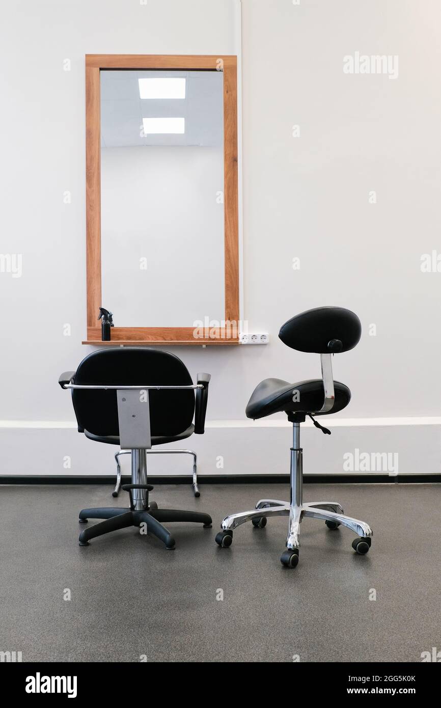 Friseursessel und Spiegel bereit, Besucher zu empfangen. Das Innere des Salons mit Friseurausrüstung und Möbeln. Stockfoto