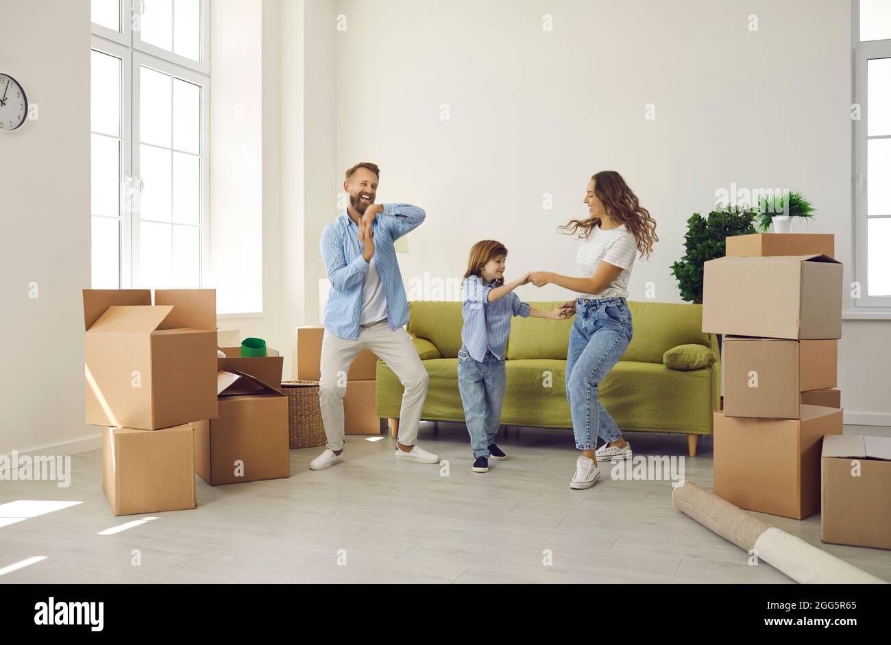 Glückliche Familie, die am Umzugstag mit ausgepackten Boxen im neuen Zuhause Spaß auf dem Zimmer hatte Stockfoto