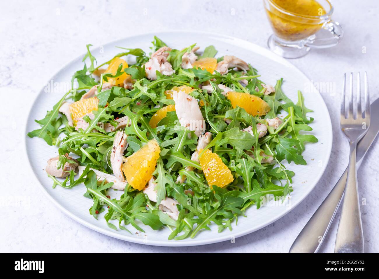 Salat mit Huhn, Orangen und Rucola. Dressing mit Olivenöl und Getreidesenf. Nahaufnahme. Stockfoto