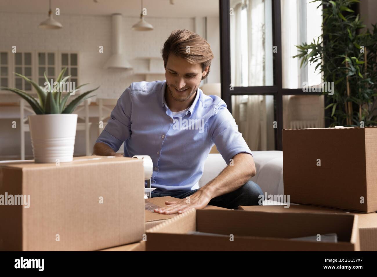 Lächelnder junger Mann, der Sachen in Kartons verpackt. Stockfoto