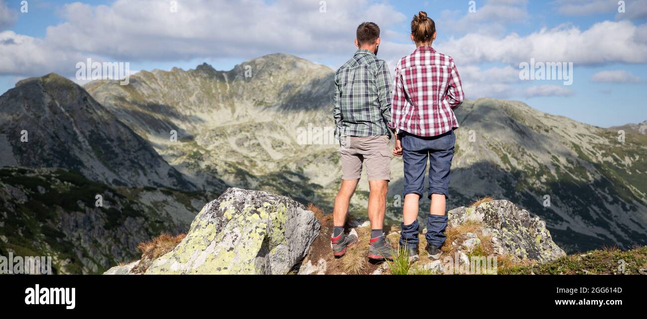 Paar sitzen auf dem Gipfel der Berge in einer herrlichen Sommerlandschaft Stockfoto