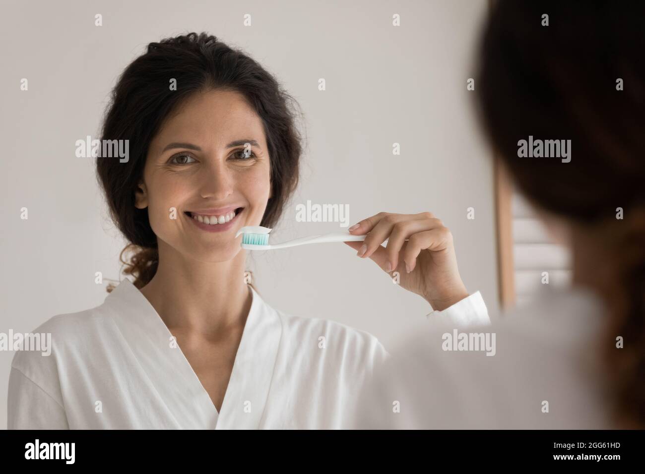 Glückliche junge schöne Frau, die zu Hause Zähne putzt. Stockfoto