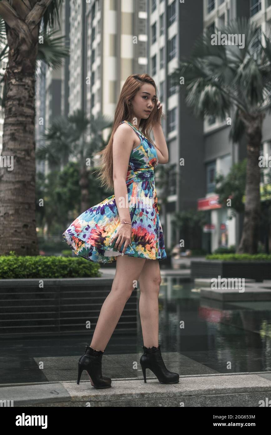 Schöne asiatische Frau in lässigen bunten Kleid zu Fuß im Freien in der Metropole. Langes Haar. Schöne Haltung. Hochwertige Fotos Stockfoto