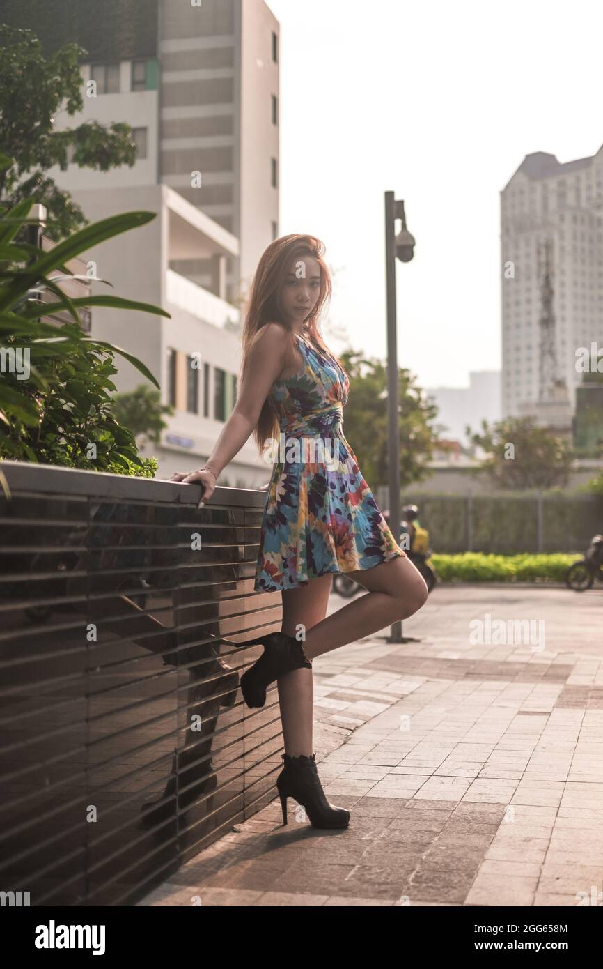 Schöne asiatische Frau in lässigen bunten Kleid auf der Straße in der Großstadt stehen. Langes Haar. Schöne Haltung. Hochwertige Fotos Stockfoto
