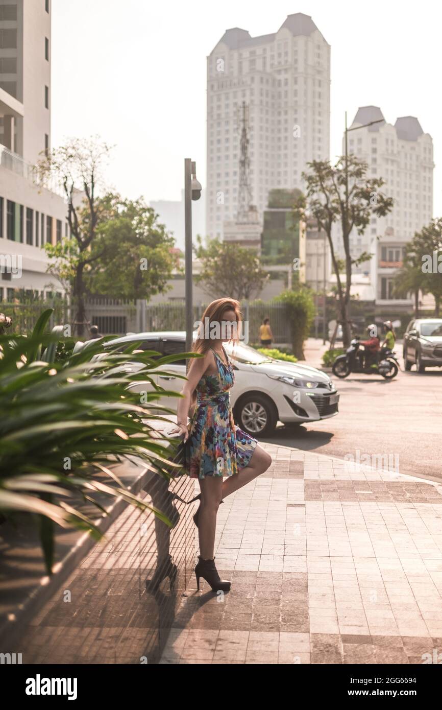 Schöne asiatische Frau in lässigen bunten Kleid auf der Straße in der Großstadt stehen. Langes Haar. Schöne Haltung. Hochwertige Fotos Stockfoto