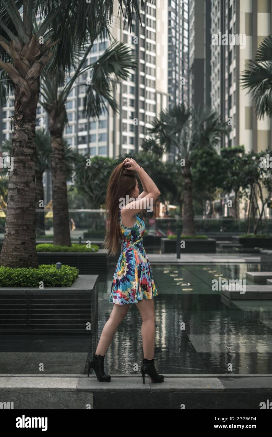 Schönheit asiatische Frau in lässigen bunten Kleid steht im Freien in der Metropole. Langes Haar. Schöne Haltung. Hochwertige Fotos Stockfoto