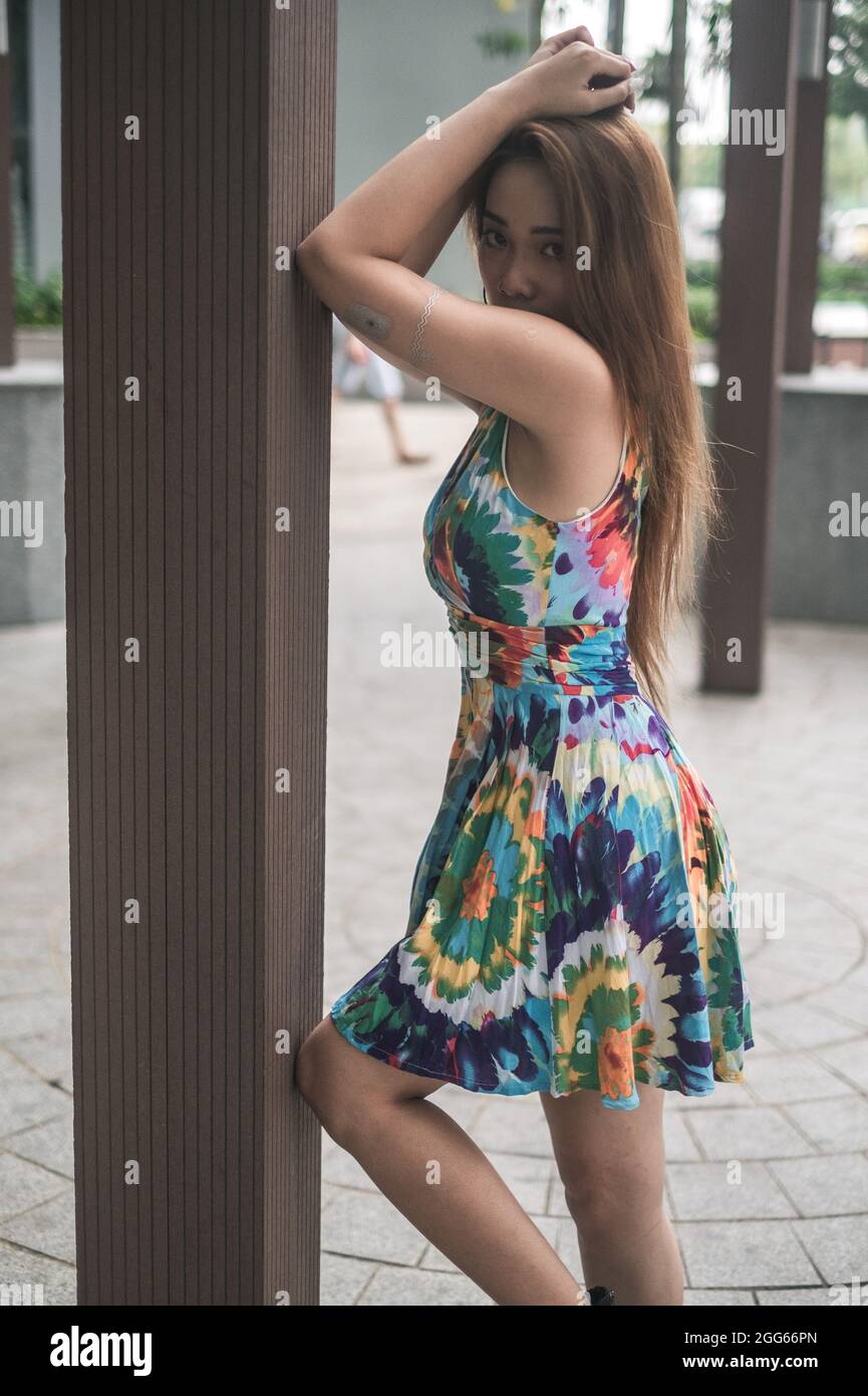 Schöne asiatische Frau in lässigen bunten Kleid im Freien stehen. Langes Haar. Schöne Haltung. Hochwertige Fotos Stockfoto