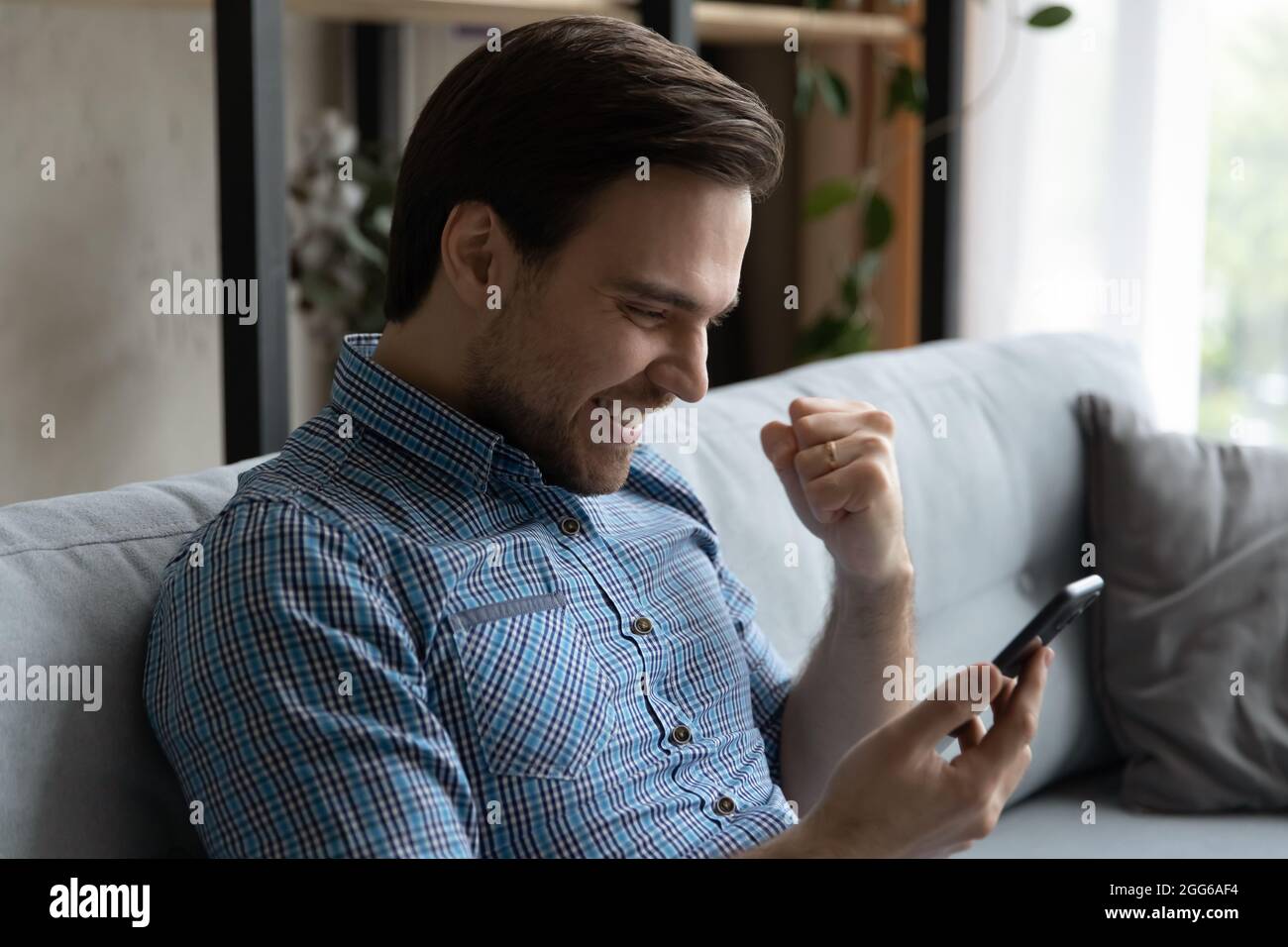 Glücklicher männlicher Smartphone-Nutzer begeistert mit SMS Stockfoto