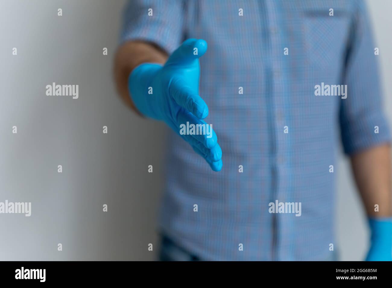 Mann mit blauen Latex-Gummihandschuhen, die Hand zum Shaken bieten Stockfoto