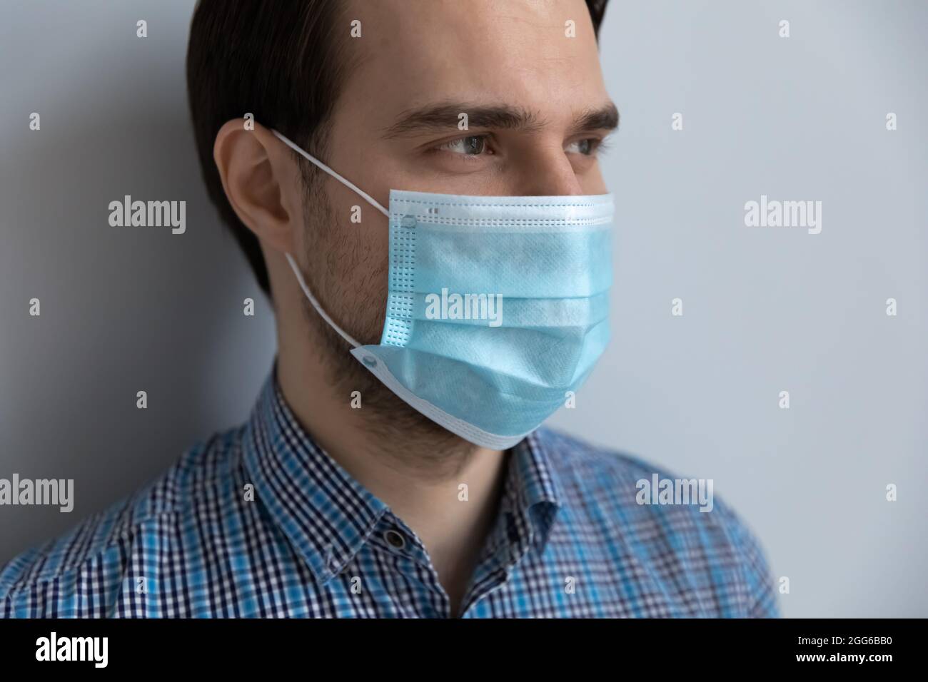 Nahaufnahme eines tausendjährigen Mannes mit blassblauer medizinischer Maske Stockfoto